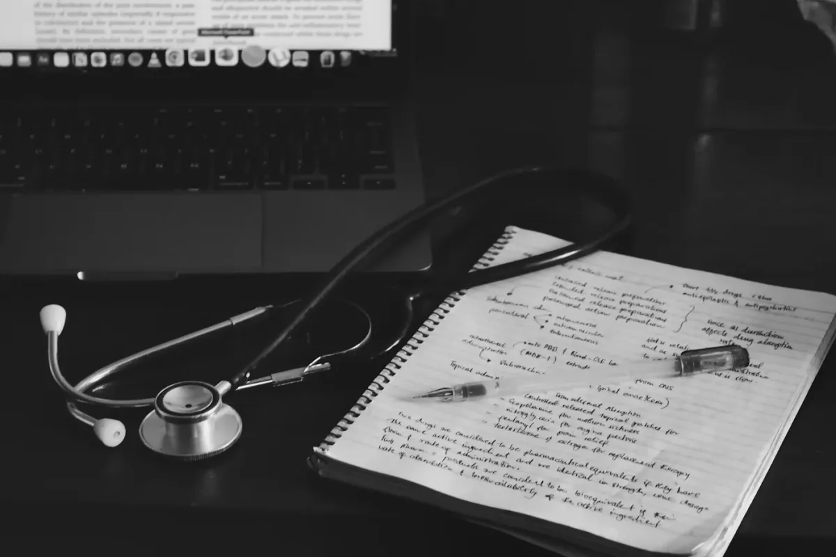 Caderno com anotações clínicas, estetoscópio e laptop
