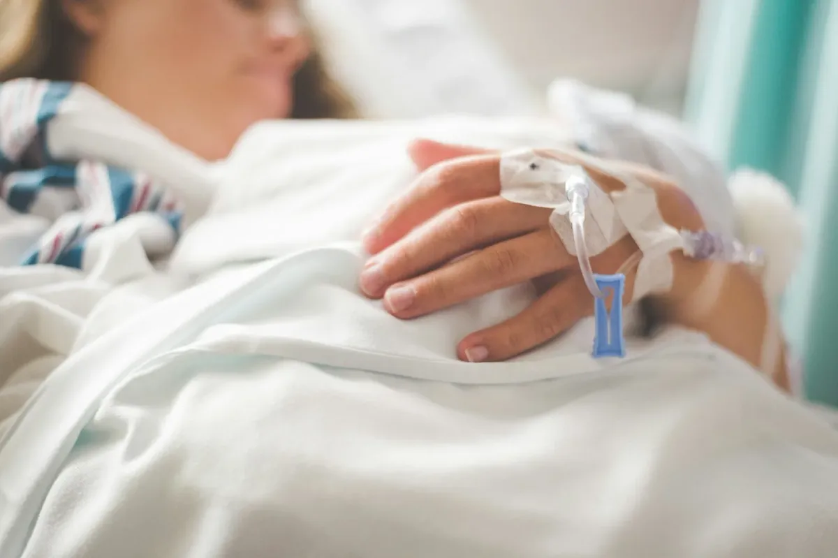 Paciente no leito hospitalar com acesso venoso no dorso da mão