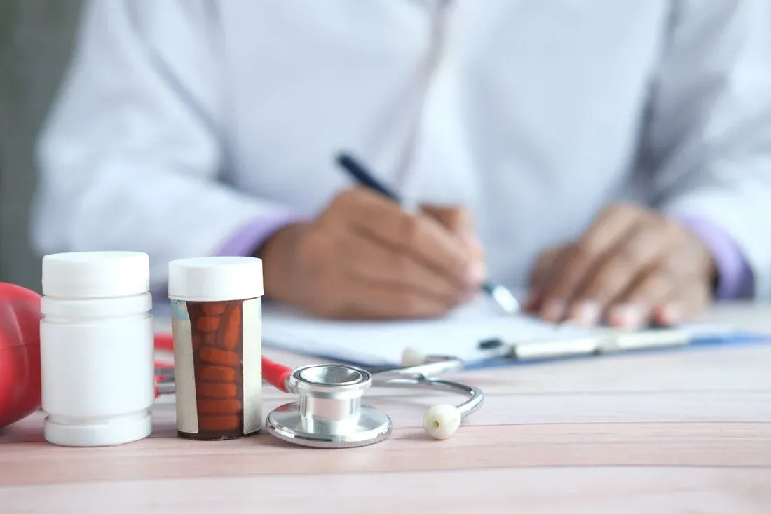 Frascos de medicamento e estetoscópio ao lado de uma prescrição