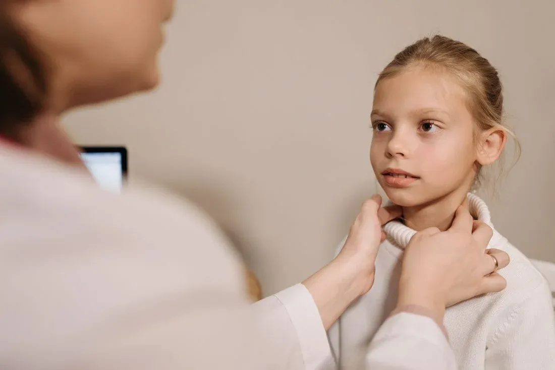 Médica palpa o pescoço de uma menina durante o exame clínico