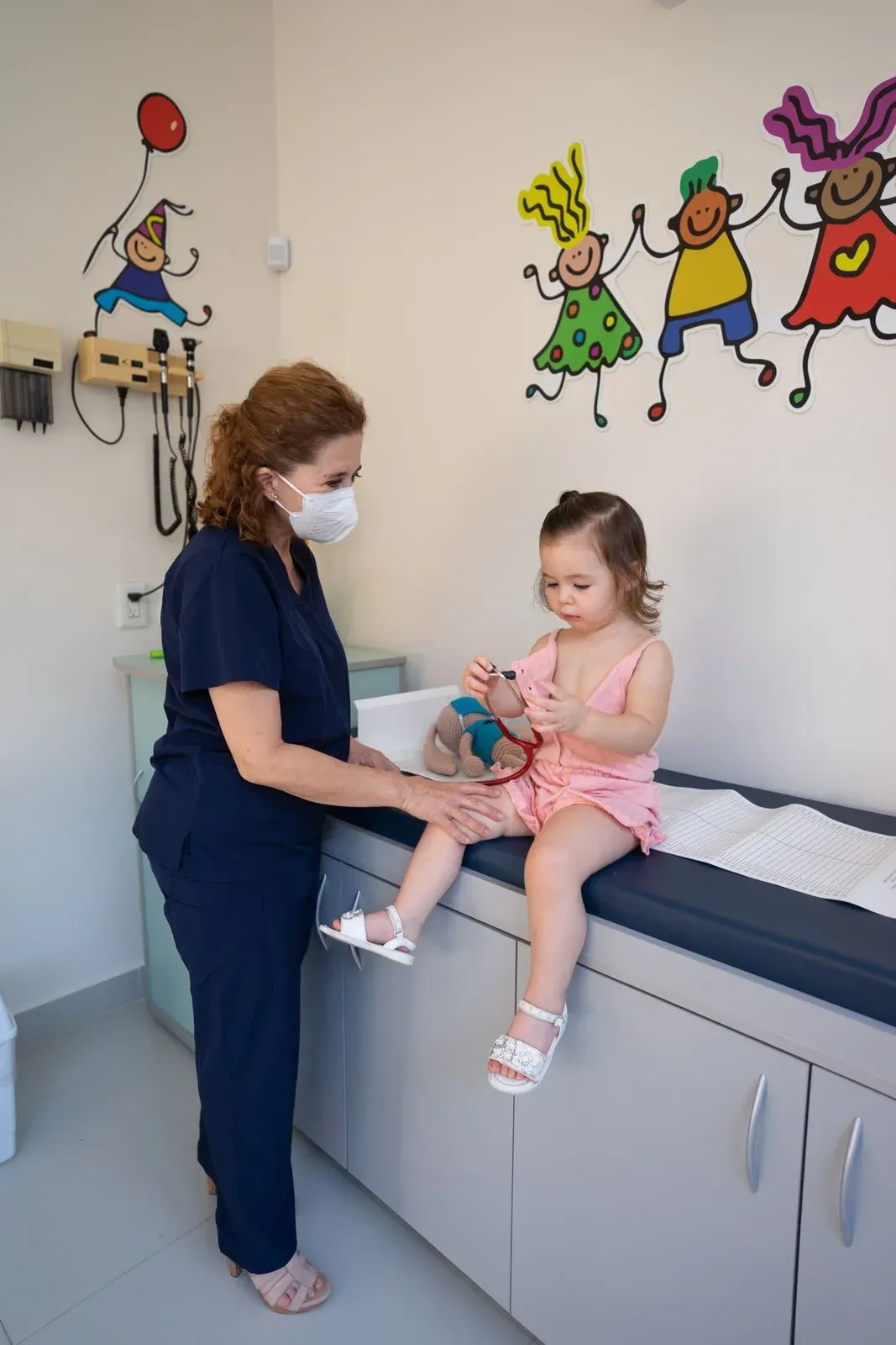 Profissional de saúde atende um bebê sobre a maca do consultório