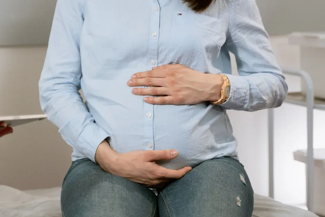 Gestante sentada com as mãos sobre o abdome