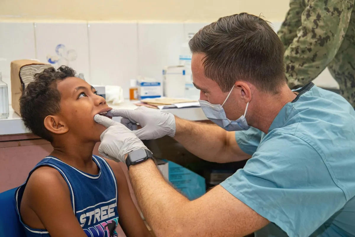 Dentista examina a boca de um menino em um consultório