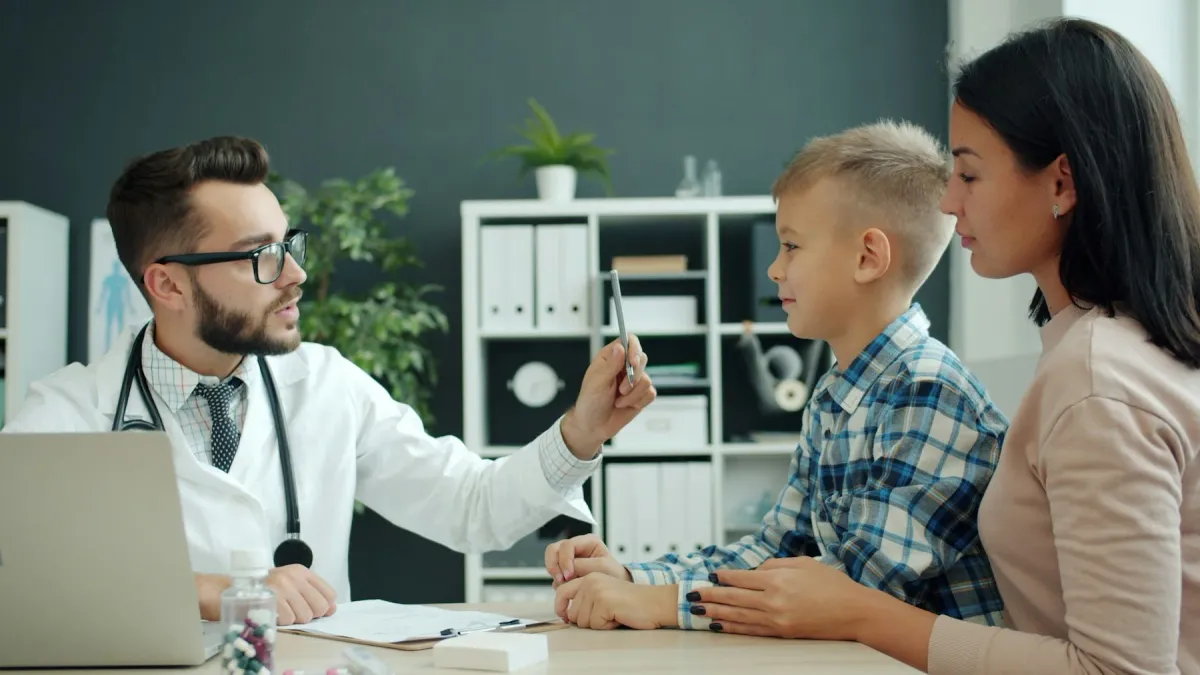 Médico examina um menino na presença da mãe no consultório
