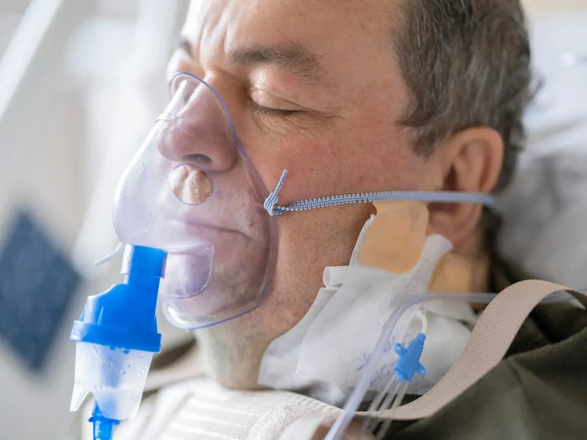 Paciente internado com máscara de oxigênio e nebulização em leito hospitalar