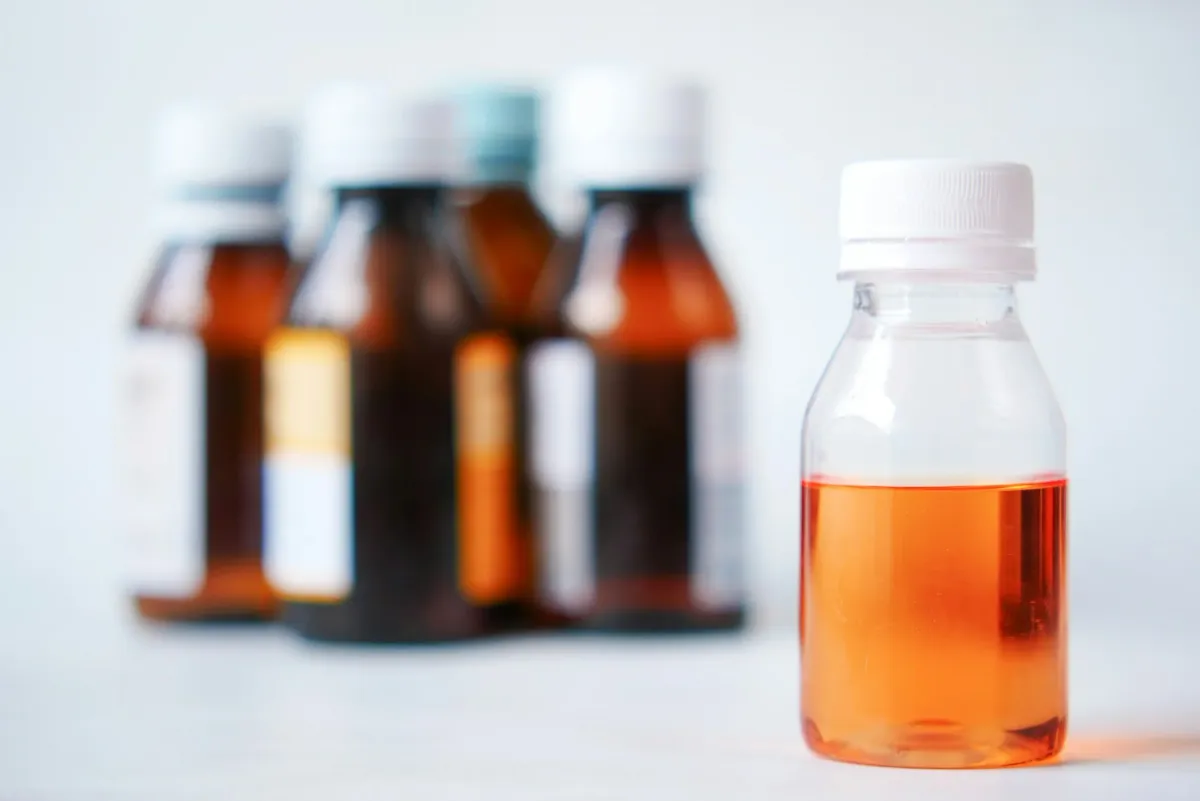 Frascos de xarope e medicamento líquido sobre uma mesa