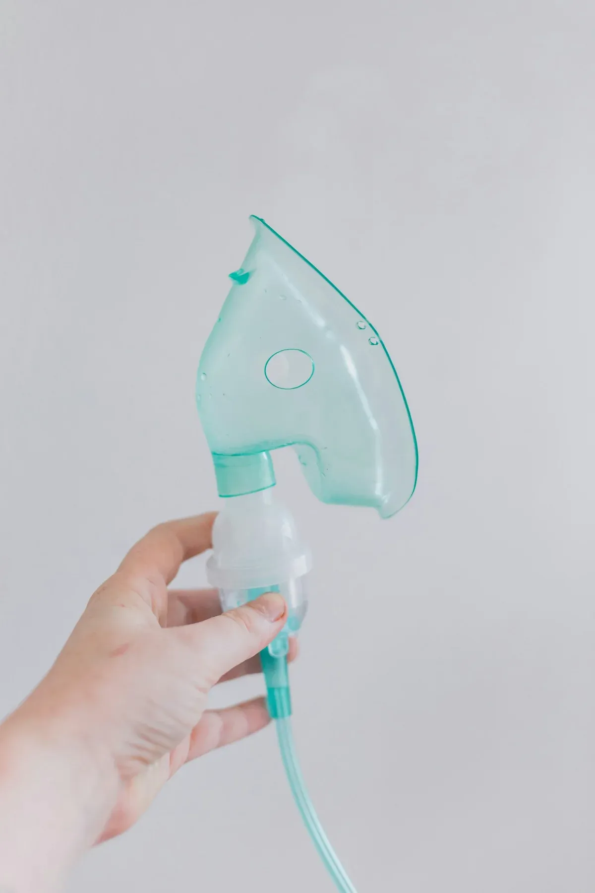 Mão segurando uma máscara de nebulização para tratamento respiratório