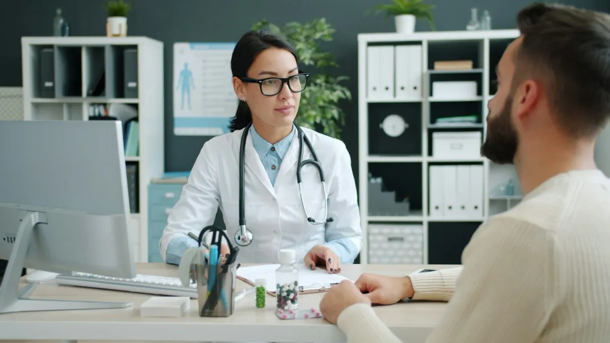 Médica de óculos conversa com um paciente no consultório