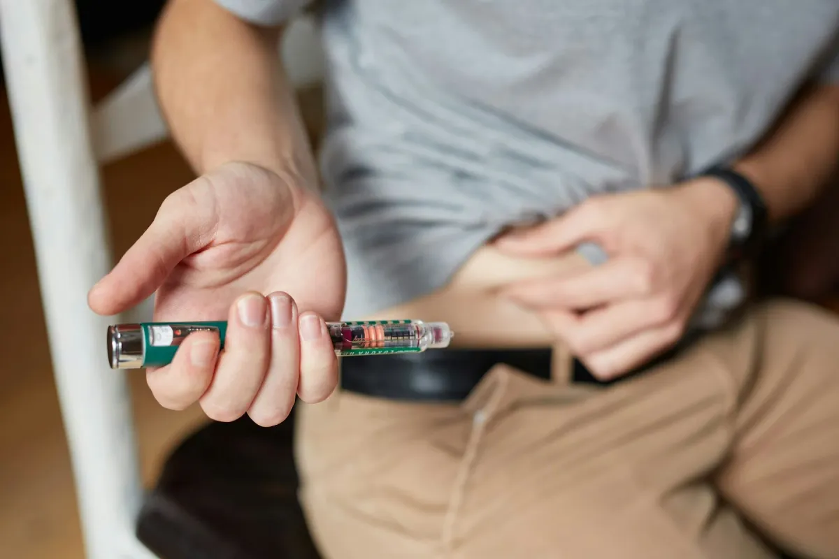 Mão segura uma caneta de insulina pronta para aplicação