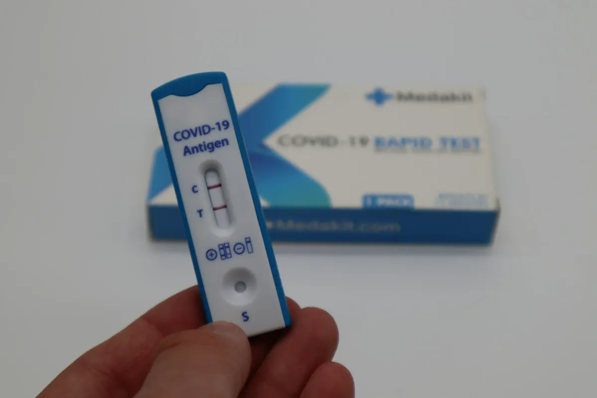 Mão segurando um teste rápido de antígeno para Covid-19 com resultado