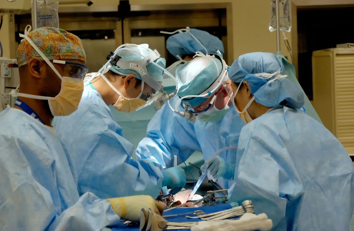 Equipe cirúrgica de máscara e avental azul operando em centro cirúrgico