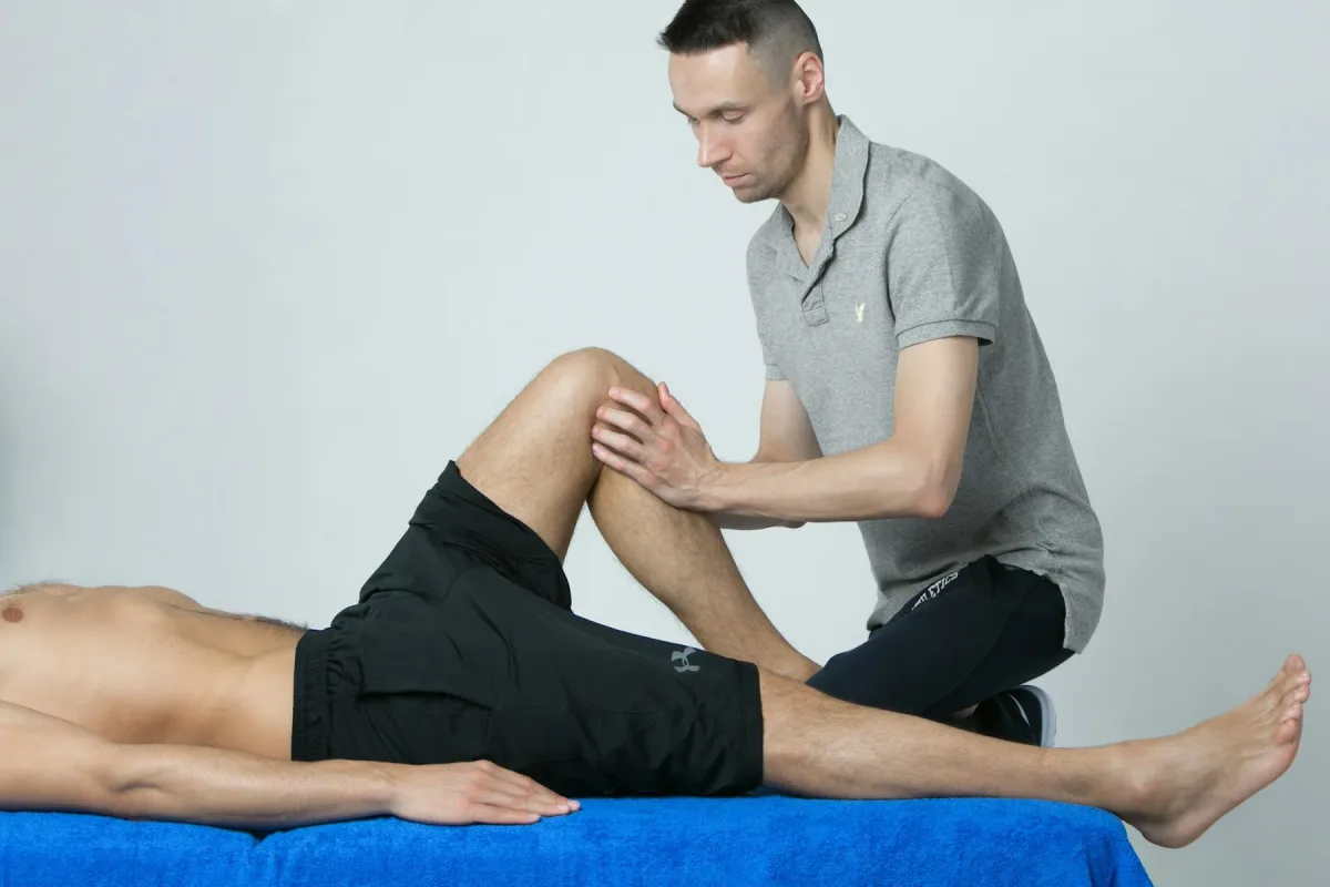 Fisioterapeuta examina o joelho de um homem deitado