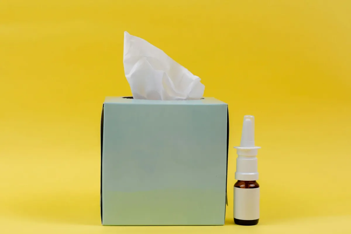 Caixa de lenços de papel ao lado de um frasco de spray nasal