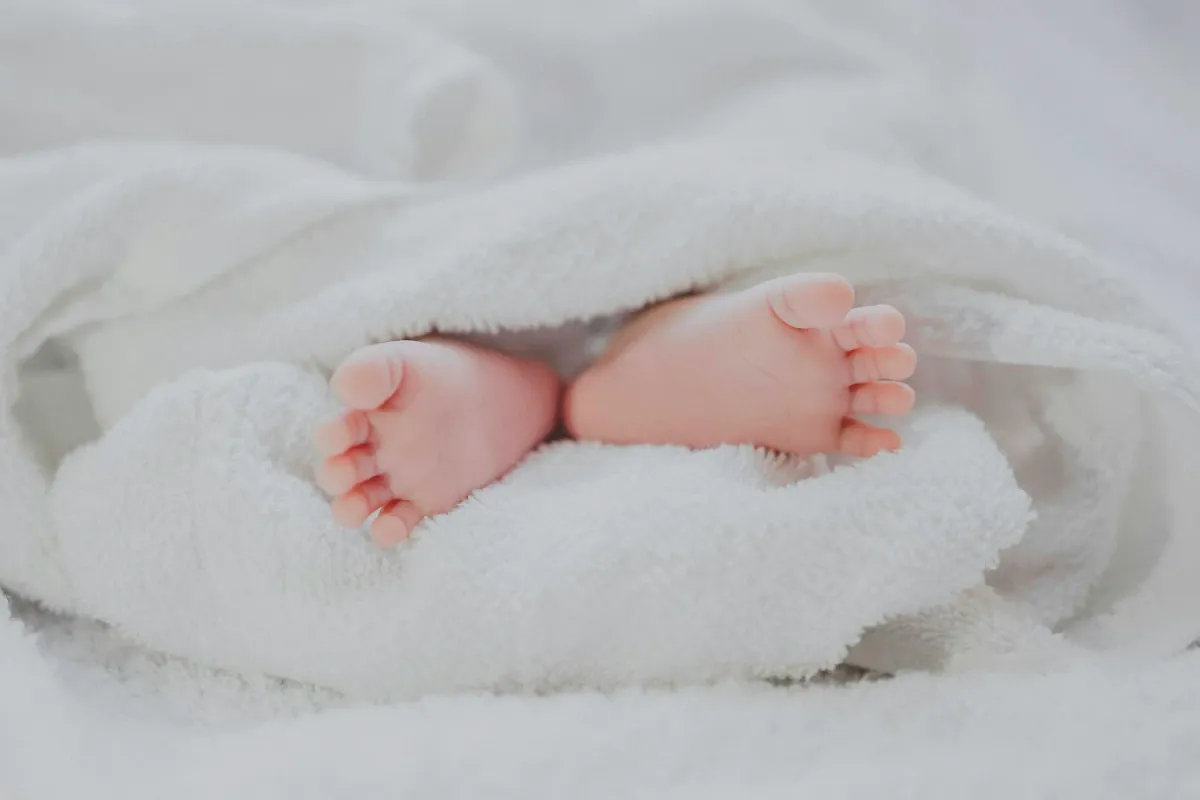 Pés de um bebê descalço aparecendo sob uma toalha branca
