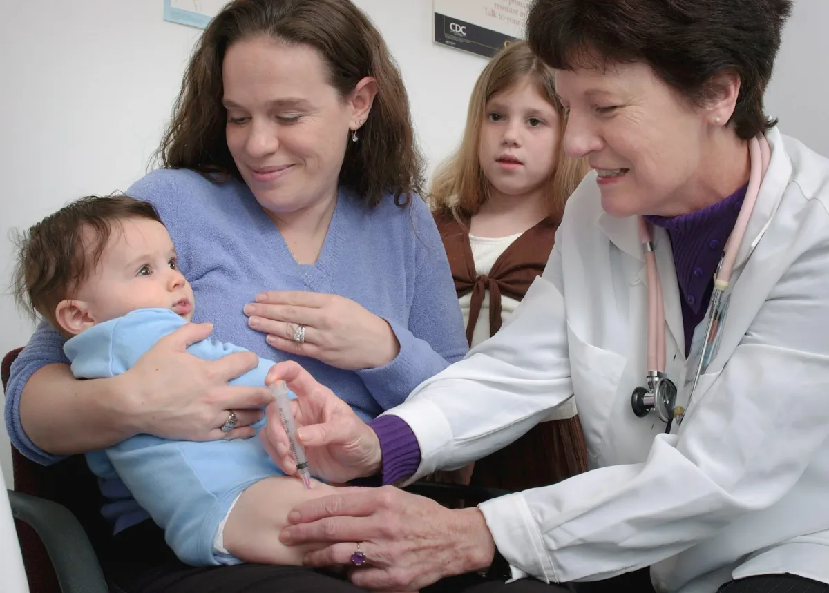 Pediatra examina um bebê no colo do pai