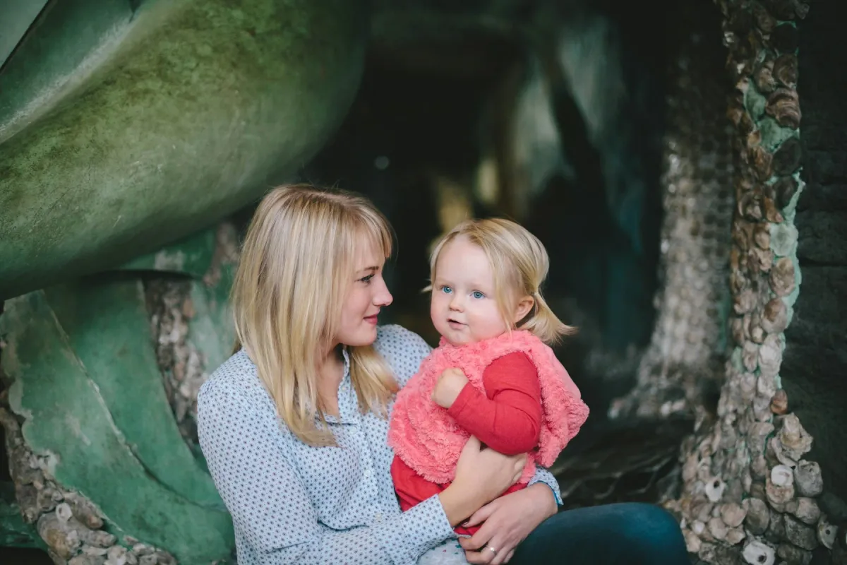 Mãe sorri com a filha pequena no colo