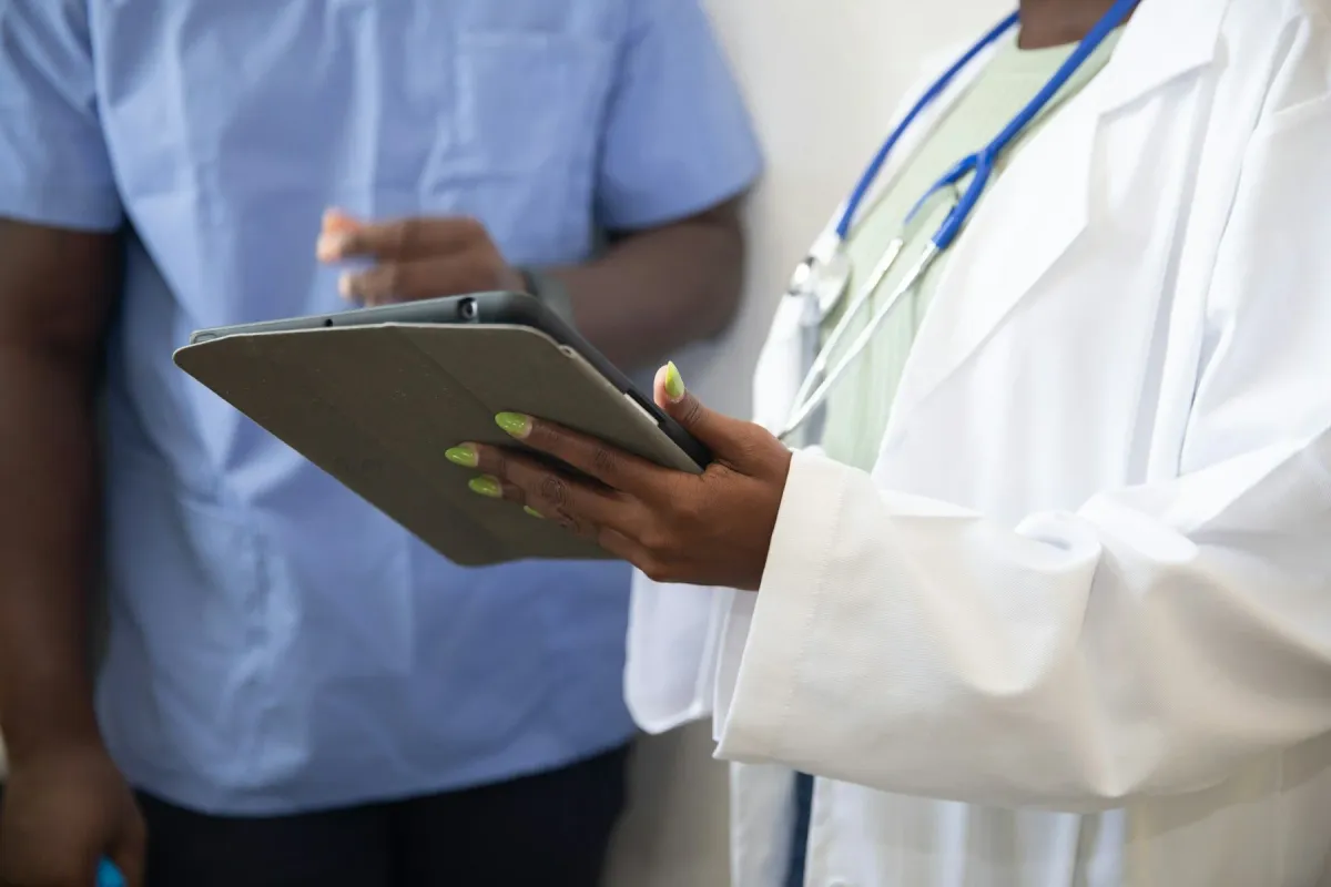 Médica de jaleco com estetoscópio consulta um tablet