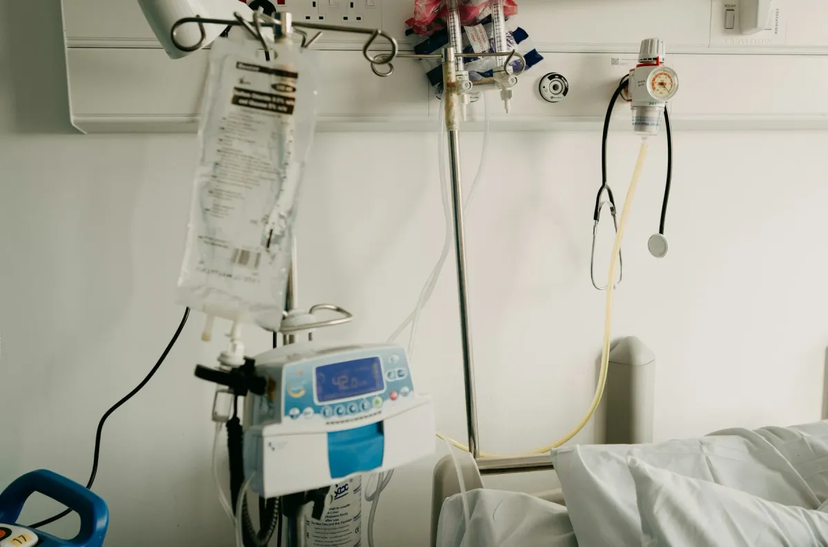 Bomba de infusão e bolsa de soro ao lado de um leito hospitalar com estetoscópio pendurado