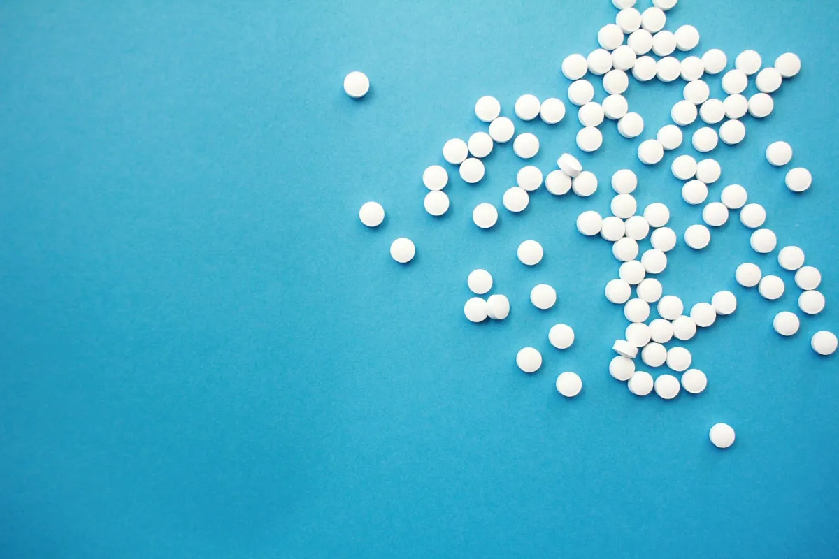 Comprimidos brancos espalhados sobre uma superfície azul