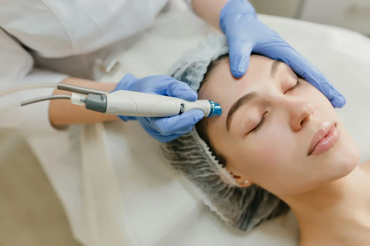 Profissional de luvas azuis realiza procedimento de cuidado facial em uma mulher