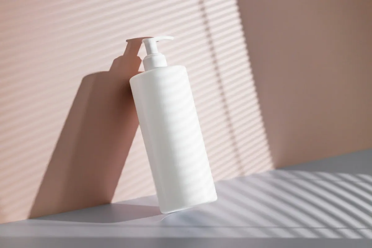 Frasco branco com válvula pump de creme ou sabonete sobre fundo rosa