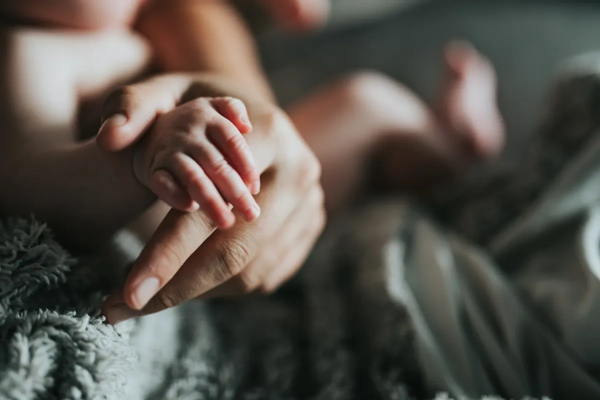 Mão de um adulto segurando a mão de um bebê