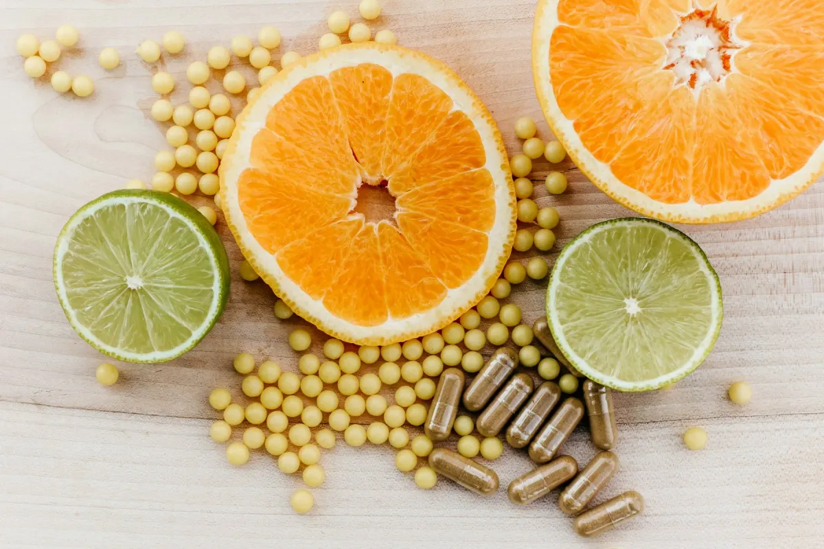 Rodelas de laranja e limão com cápsulas e esferas de suplemento sobre madeira