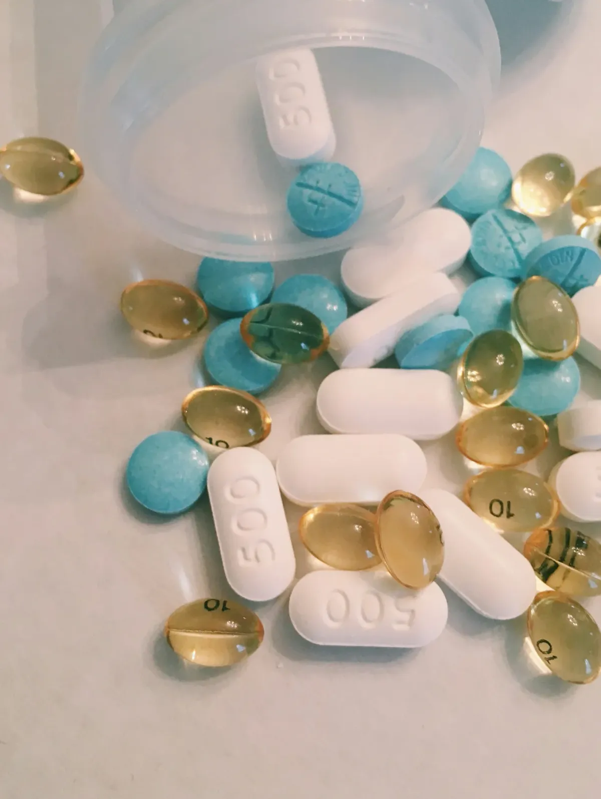 Mão segurando alguns comprimidos e cápsulas de medicamento