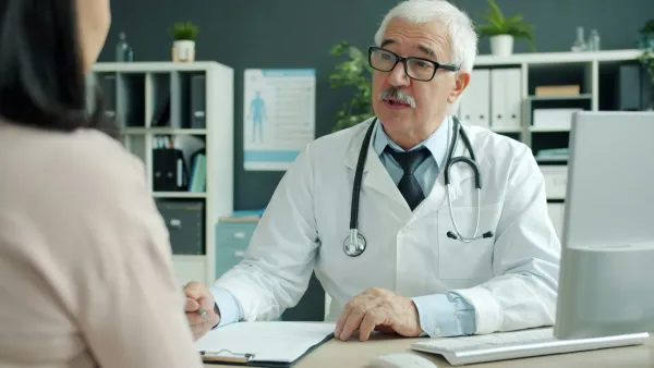 Médico conversa com paciente em consultório, com estetoscópio no pescoço