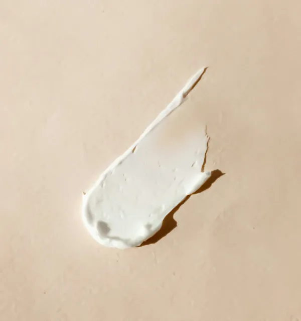 Porção de creme branco espalhada sobre superfície bege