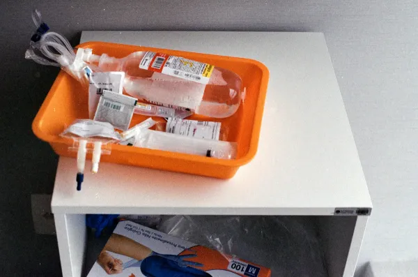 Bolsas de soro e materiais médicos em uma bandeja laranja sobre mesa branca