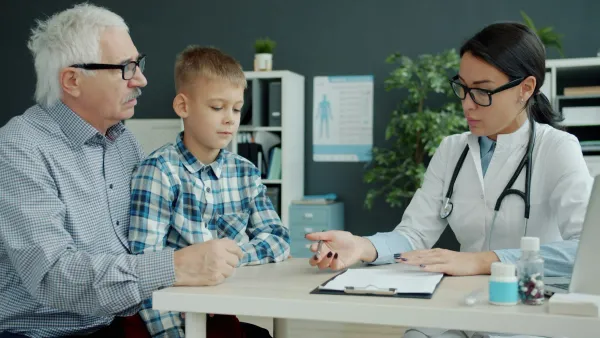 Médica conversa com um menino e o avô durante a consulta