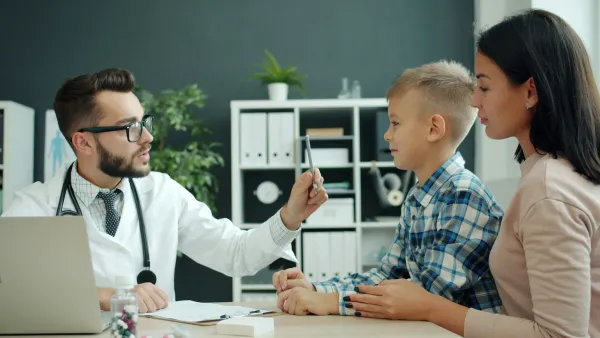 Médico examina um menino na presença da mãe no consultório