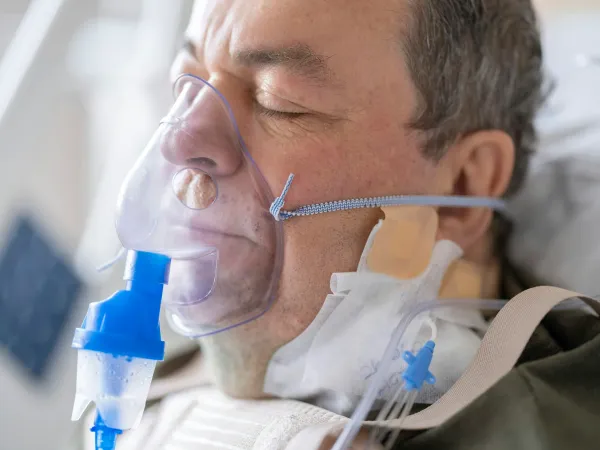 Paciente internado com máscara de oxigênio e nebulização em leito hospitalar
