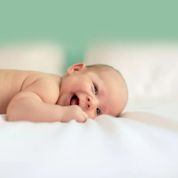 Recém-nascido deitado de barriga para baixo sobre um tecido claro