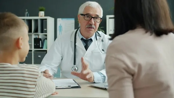 Médico conversa com a mãe e a criança durante a consulta