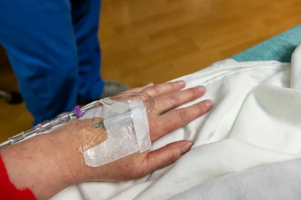 Acesso intravenoso fixado na mão de um paciente deitado
