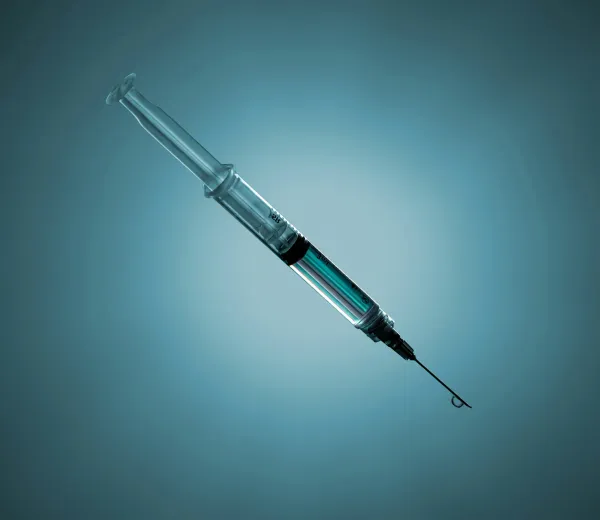 Seringa com medicamento sobre fundo azul