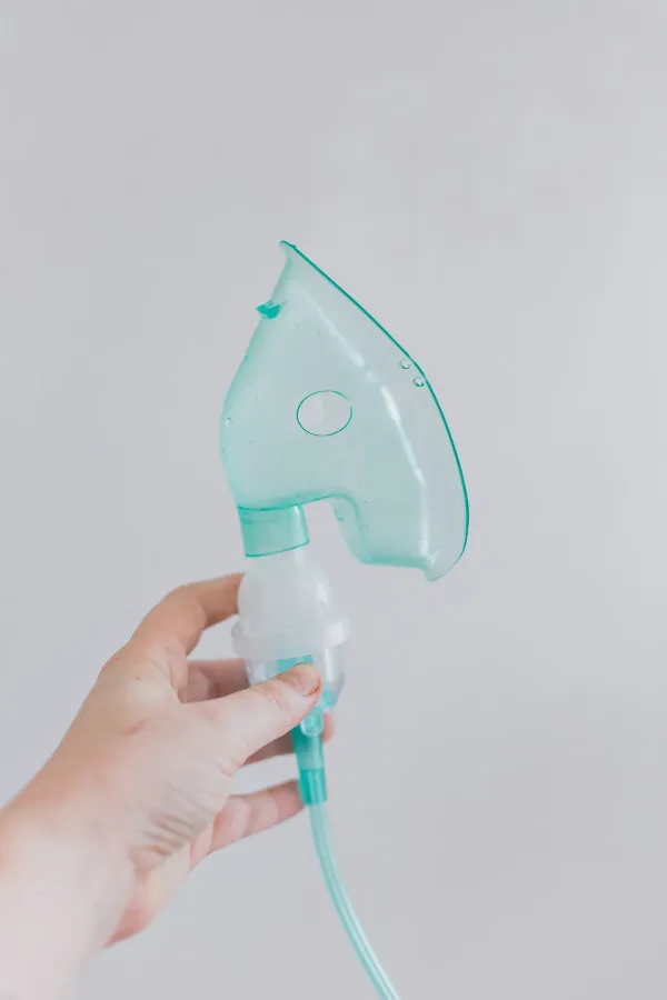 Mão segurando uma máscara de nebulização para tratamento respiratório