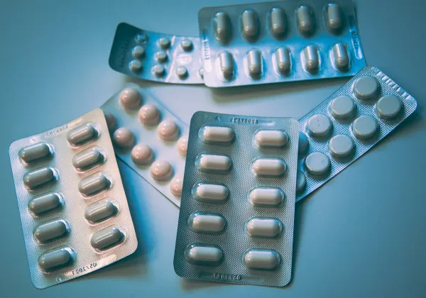 Cartelas de comprimidos brancos e azuis sobre uma superfície azul