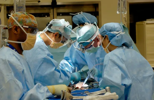 Equipe cirúrgica de máscara e avental azul operando em centro cirúrgico