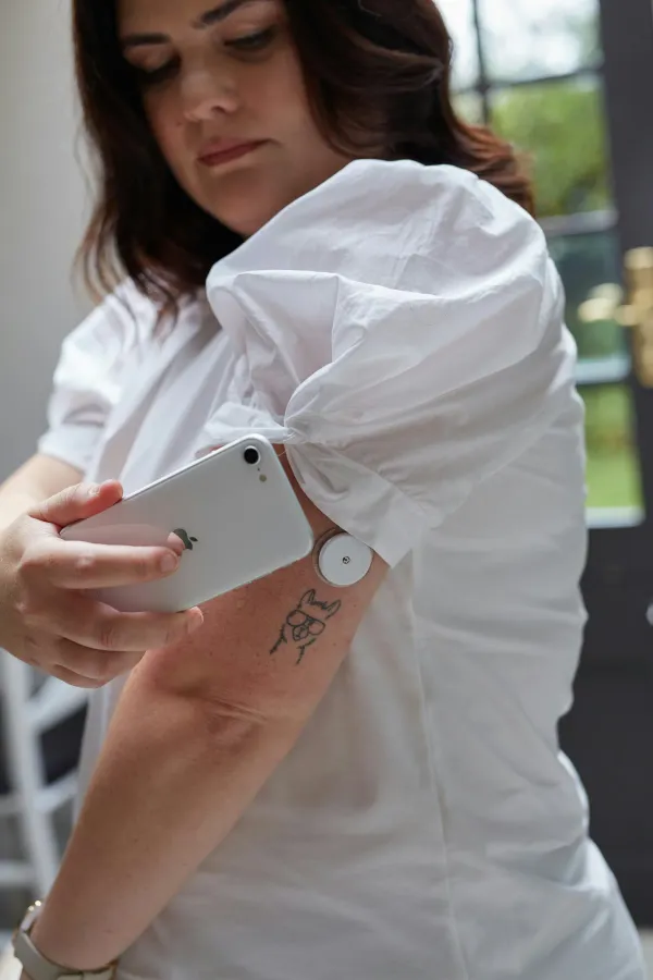 Paciente com diabetes lê a glicemia com um sensor no braço e o celular