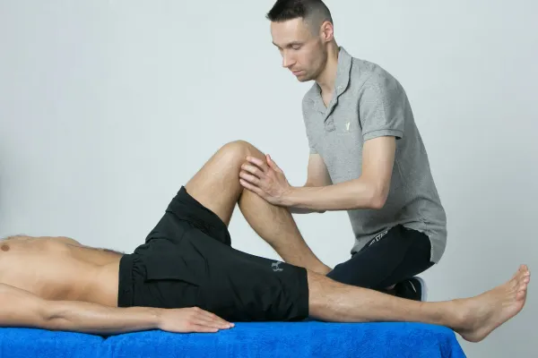 Fisioterapeuta examina o joelho de um homem deitado