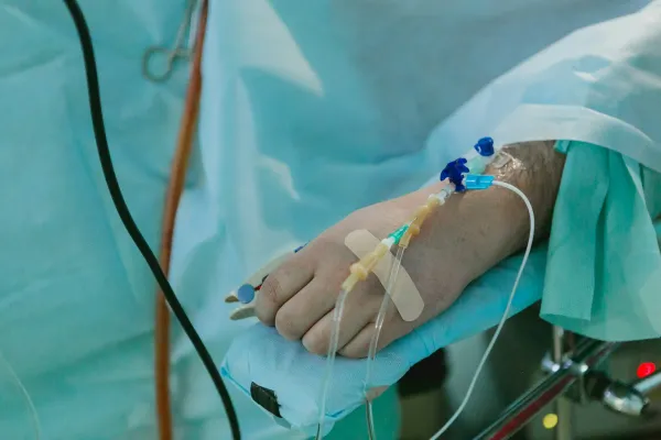 Mão de paciente com acesso venoso e equipos de infusão em ambiente hospitalar