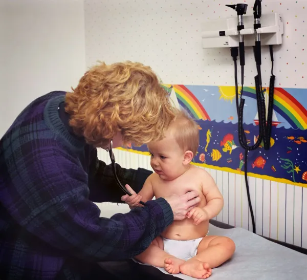 Pediatra ausculta o tórax de um bebê com estetoscópio
