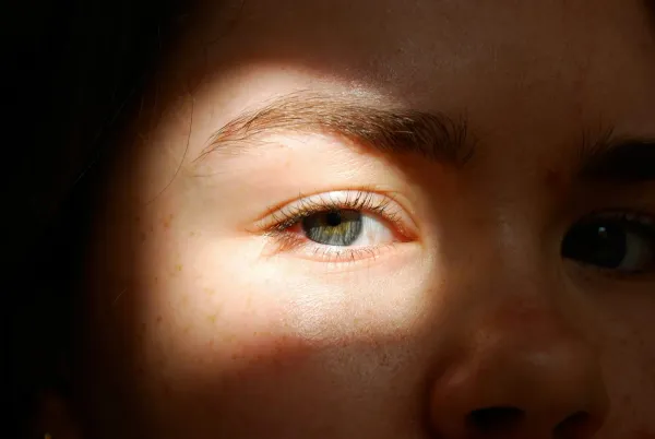 Close do olho de uma criança iluminado por uma faixa de luz