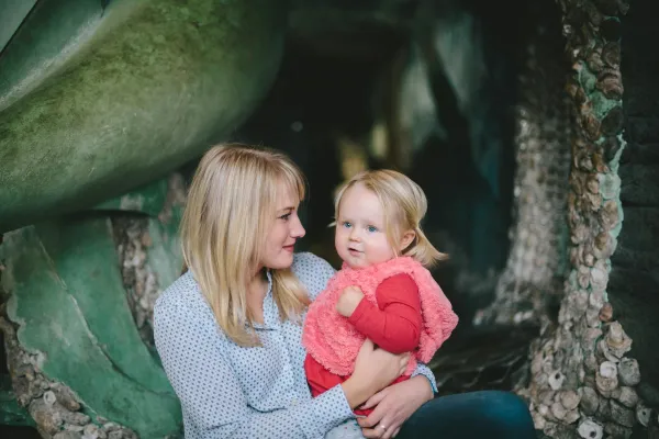 Mãe sorri com a filha pequena no colo