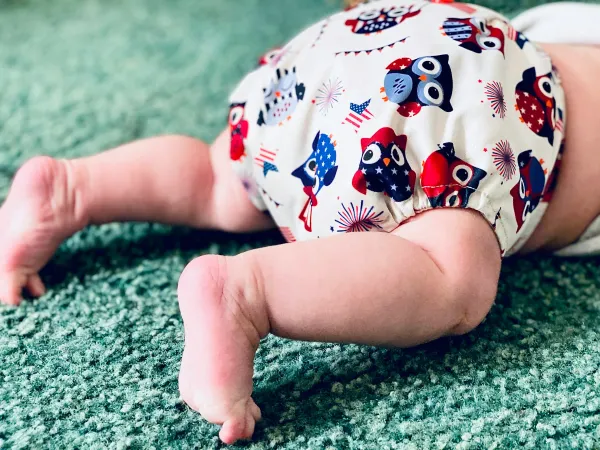 Bebê de fralda deitado de bruços mostrando as pernas e o quadril