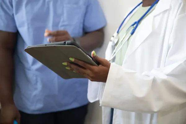 Médica de jaleco com estetoscópio consulta um tablet