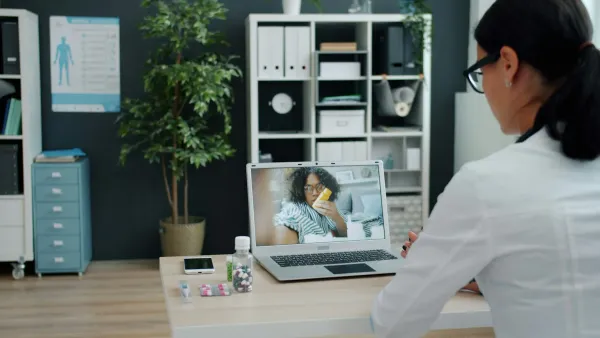Médica em consultório faz teleconsulta por videochamada no notebook com uma paciente